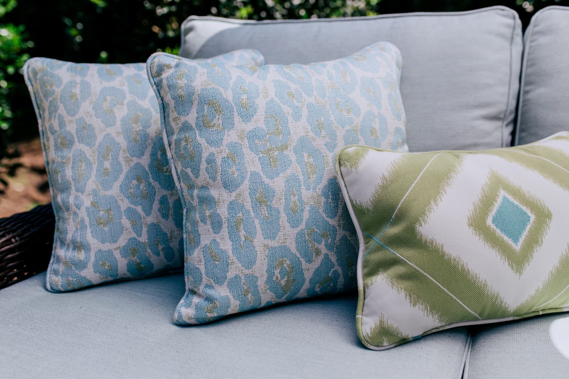 Close view of blue and green patterned outdoor pillows on a pale blue cushion