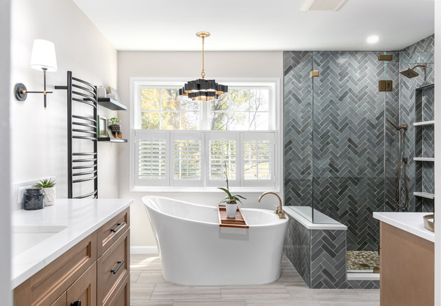 Primary bath with freestanding tub, slate herringbone tile, and brass fixtures